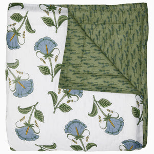 The Farah Light Indigo Bedding Collection by John Robshaw features a hand-quilted cotton voile quilt with one white side decorated with indigo and green floral motifs, and a reversed green side displaying a subtle, leaf-like pattern.