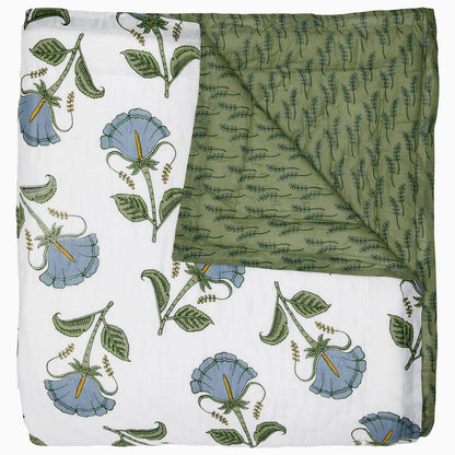 The Farah Light Indigo Bedding Collection by John Robshaw features a hand-quilted cotton voile quilt with one white side decorated with indigo and green floral motifs, and a reversed green side displaying a subtle, leaf-like pattern.