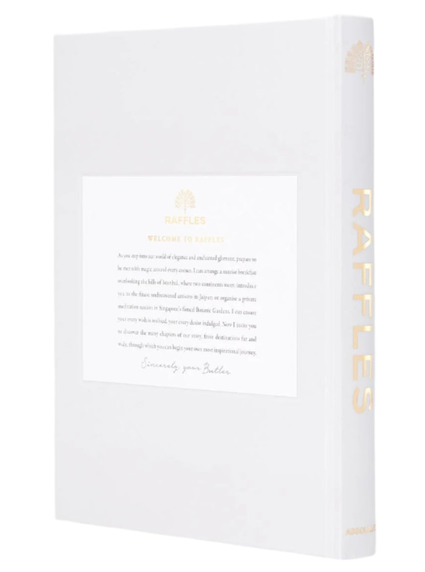 A white Assouline book named "Raffles" features a tree logo on the cover, exuding Asian charm, while gold text on the spine adds a touch of British refinement.