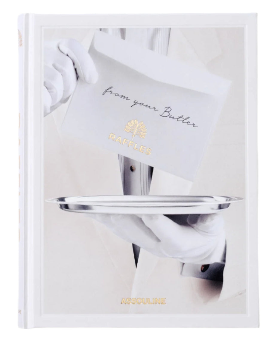 A person in white gloves offers a silver tray with an envelope marked "from your Butler" and "RAFFLES," showcasing British elegance and Asian allure. The book is titled "Raffles" by Assouline.