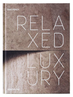 The cover of Assouline’s "Relaxed Luxury" features bold white lettering on a textured beige stone backdrop, mirroring the book’s sophisticated take on interior design.