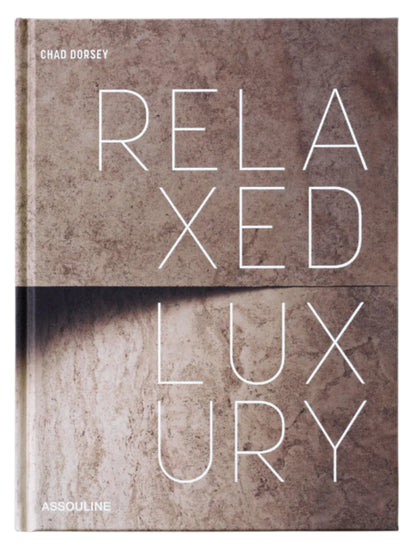 The cover of Assouline’s "Relaxed Luxury" features bold white lettering on a textured beige stone backdrop, mirroring the book’s sophisticated take on interior design.
