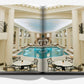 An open book displaying a photograph of an elegant indoor pool area with classical columns, decorative railings, and round tables with chairs—a scene reminiscent of the timeless beauty found in Eternally Ritz by Assouline.