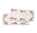 Kim Seybert Tinsel Bow table runner with white fabric, scalloped gold edges, and embroidery featuring red ribbons, pine sprigs, candy canes, and ornaments.