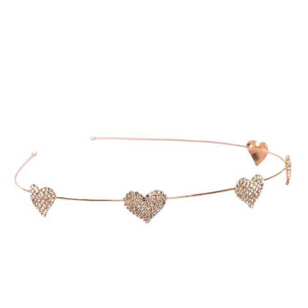 The Great Pretenders Boutique Rhinestone Heart Headband features a delicate, rose gold band elegantly adorned with three heart-shaped designs encrusted with small crystals for a luxurious sparkle.