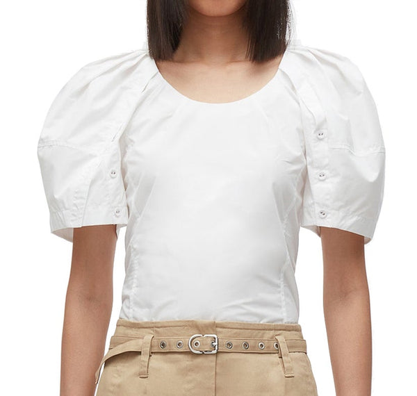 Woman wearing a 3.1 Phillip Lim Bloom Sleeve Scoop Neck Top with puff sleeves and high-waisted beige trousers.
