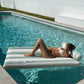 A woman relaxes on the Sunnylife Luxe Lilo Green Stripe pool float, enjoying clear blue water and sunny vibes—perfectly capturing Australian summer style.