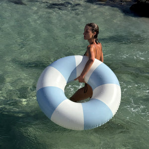 A person stands in shallow, clear water holding the Sunnylife Poolside Tube Float in Duck Egg Blue, capturing the classic Australian summer vibe from the ultimate summer lifestyle brand.