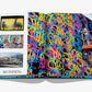 The open book, "Street Art Icons: Wynwood Walls" by Assouline, showcases vibrant street art photos on the left and a colorful graffiti wall with an artist on a lift on the right, celebrating urban renewal's brilliance.