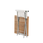 The Sundeck Folding Director's Footrest by Summit Furniture, with its wooden and metal design inspired by campaign furniture, stands upright against a perforated wooden panel.