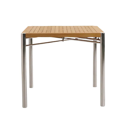 The Sundeck Folding Table by Summit Furniture features a square perforated teak top and four cylindrical marine-grade stainless steel legs, inspired by classic campaign furniture, shown front view against a white background.