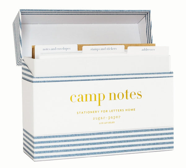 The Sugar Paper Camp Notes Box, a striped storage box by Sugar Paper, contains a stationery set with sections for notes, envelopes, stamps, stickers, and addresses.