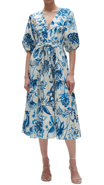 A person wearing a Figue Joyce Dress, a blue and white floral print midi-length dress with balloon sleeves and heeled sandals, crafted from chintz cotton poplin.