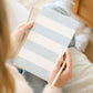 A person holds a Sugar Paper Blue Striped Weekly Pad and pencil while seated, with an organized notebook on their lap.