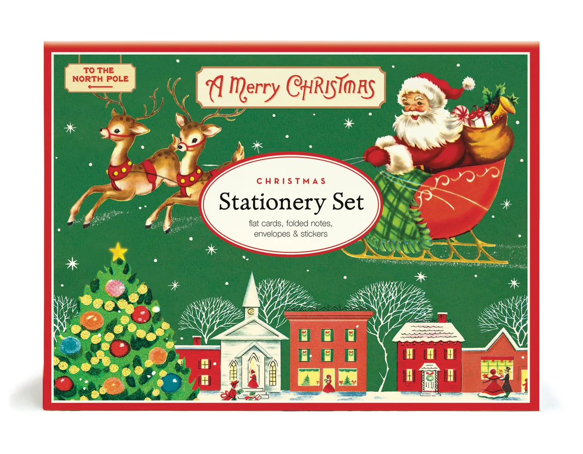 A vintage Cavallini Papers and Co. Christmas Stationery Set in a green box featuring Santa in a sleigh above a snowy village, including flat cards, folded notes, envelopes, and stickers.