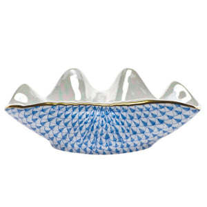 The Herend Clam Shell Collection features a white porcelain bowl with a wavy rim, gold trim, and hand-painted blue fish scale pattern, inspired by classic Herend porcelain design.