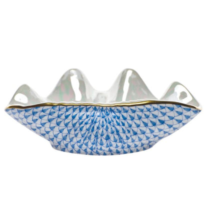 The Herend Clam Shell Collection features a white porcelain bowl with a wavy rim, gold trim, and hand-painted blue fish scale pattern, inspired by classic Herend porcelain design.