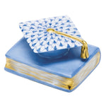 The Herend Graduation Cap is a collectible porcelain box shaped like a book, featuring a blue finish and gold-trimmed cap on top to add timeless elegance to any space.