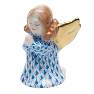 The Herend Praying Angel porcelain figurine features red hair, gold wings, and a hand-painted blue patterned dress, posed with hands clasped in prayer against a white background.