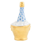 Herend Champagne Bucket: This exquisite porcelain figurine depicts a champagne bottle with delicate blue and gold accents, nestled in an ice bucket surrounded by realistic white ice cubes. Expertly crafted from durable porcelain, the Herend Champagne Bucket features masterfully hand painted details that enhance its refined elegance.