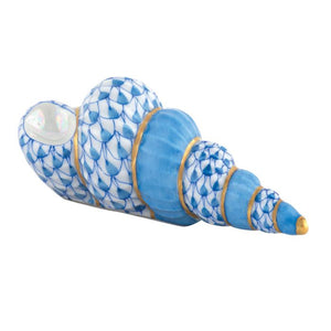 The Herend Staircase Shell Collection features a ceramic seashell figurine with a blue and white scale pattern, gold accents, and iridescent detail, inspired by classic hand-painted designs.