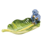 The Herend "Monkey on Banana Leaf" is a collectible porcelain dish featuring a blue-and-white patterned monkey figurine on a green leaf, accented with gold—an elegant decorative piece for any space.