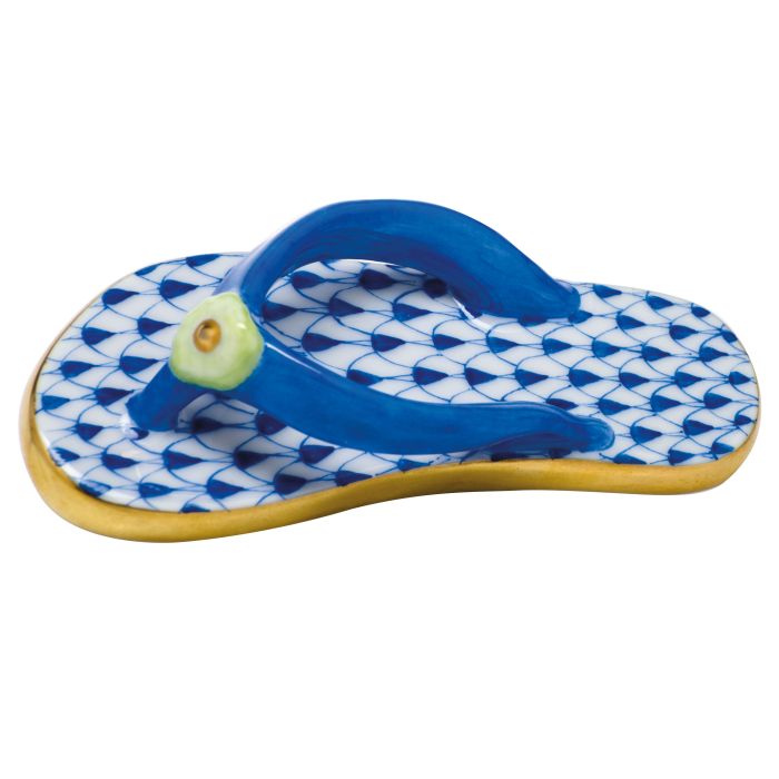 The Herend Flip Flop is a collectible porcelain piece with blue straps, a gold-edged sole, and a patterned blue and white base—a timeless decorative accent.