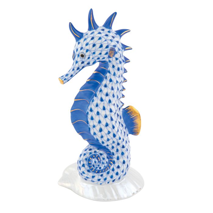 The Herend "Seahorse on Scallop Shell" is a hand-painted porcelain figurine in blue and white fishnet with gold accents, standing on a white base—a charming decorative accent for any space.