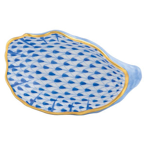 The Herend Oyster Shell plate features a blue and white ceramic seashell shape, gold rim, and geometric fish scale pattern—a timeless decorative accent.