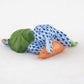 The Herend Slumber Bunny is a handcrafted Hungarian porcelain figurine featuring a blue fishnet motif rabbit lying on its side, holding a carrot, and detailed with a green leaf on its back, set against a plain white background.