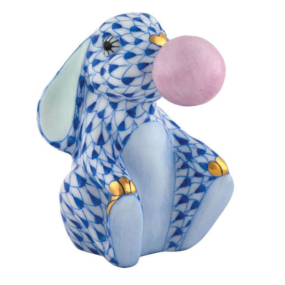 Herend’s Bubble Gum Bunny is a blue and white porcelain rabbit with gold-tipped paws, playfully blowing a pink bubble—a charming decorative piece with lasting appeal.