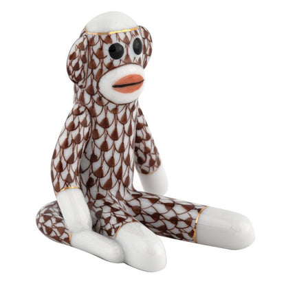 Herend Sock Monkey porcelain figurine, hand painted in the brand’s signature brown fishnet pattern with white feet, hands, and face plus orange lips; shown sitting upright against a white background.