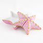 From the Starfish Box Collection by Herend, this decorative porcelain box features a starfish shape, hand-painted pink, white, and gold patterns on a removable lid, and a white interior.