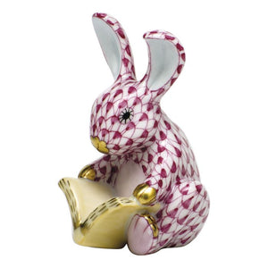 Herend's Storybook Bunny is a porcelain collectible featuring a pink-patterned rabbit with gold accents, sitting upright and holding an open yellow book—a decorative accent that brings timeless elegance to any space.