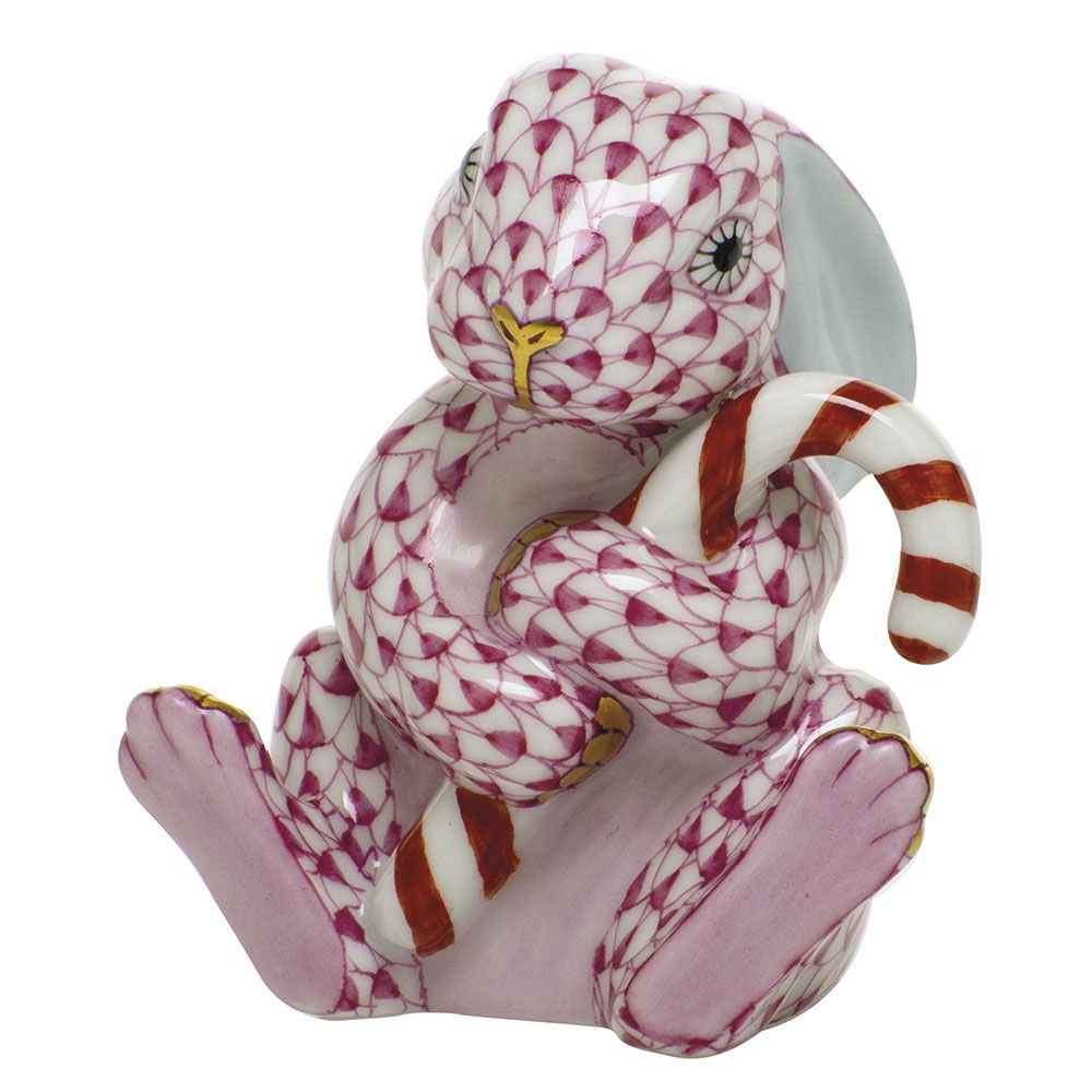 The Herend Candy Cane Bunny is a porcelain figurine featuring a pink rabbit with a delicate scale pattern, holding a red and white striped candy cane—a charming addition to your holiday décor and an ideal collectible for festive enthusiasts.