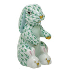 The Herend Bunny Slippers is a hand-painted porcelain collectible figurine of a rabbit in green fish scale, sitting upright and wearing tiny bunny slippers—a delightful decorative accent for any space.