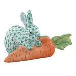 Herend's Carrot Love is a porcelain figurine featuring a green and white rabbit atop an orange carrot with green leaves, adding timeless elegance to any space.