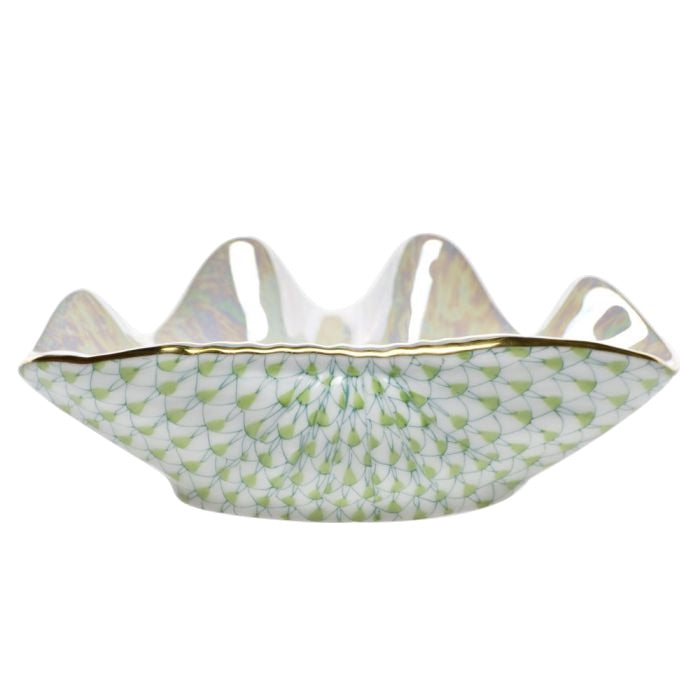 The Herend Clam Shell Collection features a white porcelain bowl with a wavy rim, gold accents, and a green geometric fish scale pattern inspired by classic Herend designs.