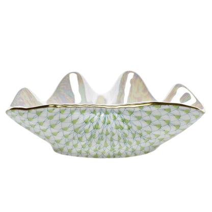The Herend Clam Shell Collection features a white porcelain bowl with a wavy rim, gold accents, and a green geometric fish scale pattern inspired by classic Herend designs.
