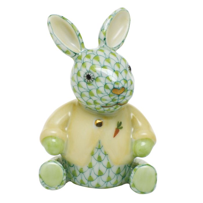The Herend Sweater Bunny is a ceramic figurine inspired by the iconic porcelain bunny, featuring a green and white fishnet motif, yellow sweater, and carrot detail—handcrafted in Hungary.