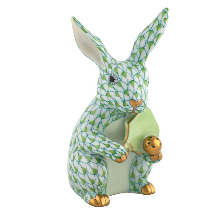 The Herend Pickleball Bunny is a collectible porcelain rabbit figurine with a green fishnet pattern and gold accents, holding a green pickleball—an elegant decorative accent with timeless appeal.