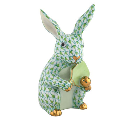 The Herend Pickleball Bunny is a collectible porcelain rabbit figurine with a green fishnet pattern and gold accents, holding a green pickleball—an elegant decorative accent with timeless appeal.