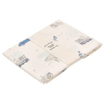 The Gooselings Transit Treasures Swaddle is a folded cream-colored 100% cotton muslin blanket with blue and gray vintage vehicles, including cars, airplanes, and hot air balloons.