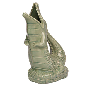 The Original Gluggle Jug's Croggle Jug is a green ceramic sculpture shaped like an upright crocodile with an open mouth, displayed on a textured base.