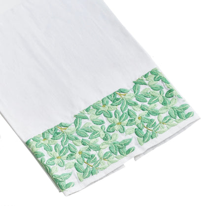 Boxwood Bath Collection by Haute Home – Italian white linen fabric with a green floral-embroidered border showcasing leafy motifs along the edge, photographed on a plain white background. Ideal for use as a tissue box cover or tip towel.