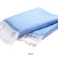 A neatly folded light blue Pezzo Throw by Matouk, crafted from brushed cotton with white fringed edges, displayed on a white background. "Azure" is written below the blanket.