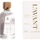 A clear glass bottle of L'Avant Collective Fresh Linen Scent Collection room spray is displayed next to its elegant white and gold box; the collection also includes hand soap and laundry detergent.