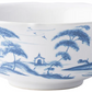 From Juliska’s Country Estate Delft Blue Dinnerware Collection: a white porcelain bowl adorned with a blue pastoral scene of trees, birds, buildings, tents, and countryside charm near a horse stable.