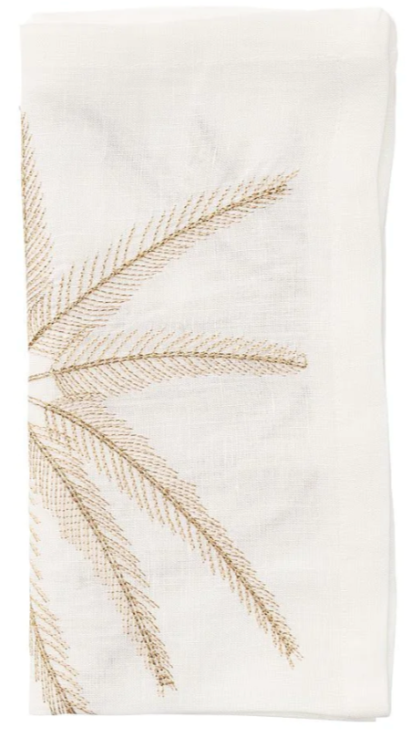 The Kim Seybert Palm Coast Napkin Set features folded white cloth napkins with gold embroidered palm fronds—an elegant accent for your coastal dining table.