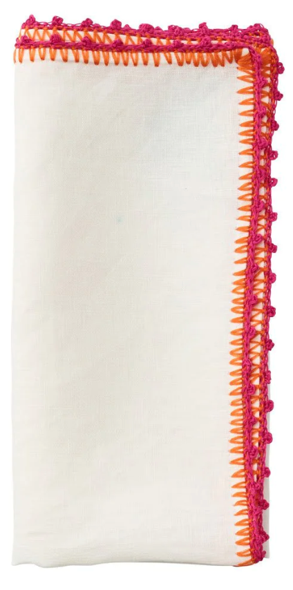 The Kim Seybert Knotted Edge Napkin Set features white 100% linen napkins, folded rectangularly, with orange and pink decorative edge stitching.